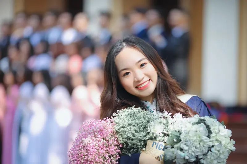Một nhóm học sinh cầm hoa hướng dương chụp kỷ yếu, thể hiện sự tươi trẻ và năng động.