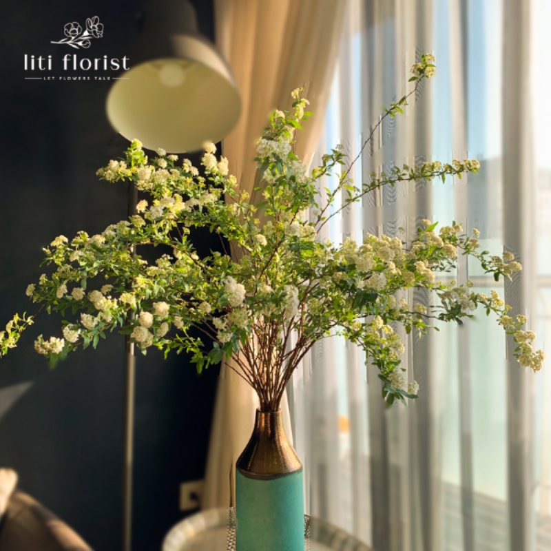 Bình hoa đào đông thật kết hợp với lá xanh, tạo nên sự tương phản màu sắc hài hòa cho không gian Tết