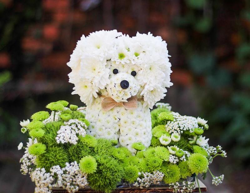 Một bó hoa được cắm nghệ thuật với các loại hoa từ Dalat Hasfarm, đặt trên bàn làm việc, thể hiện sự kết hợp giữa nguồn hoa chất lượng và kỹ năng cắm hoa từ Lela Flower